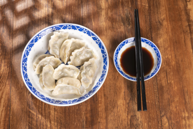 传统美食水饺盛放在青花碟子中摆放在窗影下的木桌上旁边放有中国结