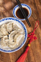 传统美食水饺盛放在青花碟子中摆放在窗影下的木桌上旁边放有中国结