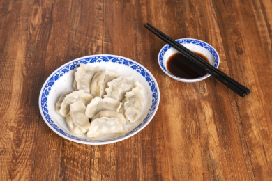 传统美食水饺盛放在青花碟子中摆放在窗影下的木桌上旁边放有中国结