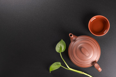 窗影下的黑色桌面上摆放着传统茶具紫砂壶及紫砂杯