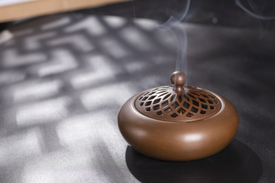 窗影下的黑色桌面上摆放着紫铜香炉