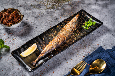 深色背景下放在盘子里的秋刀鱼