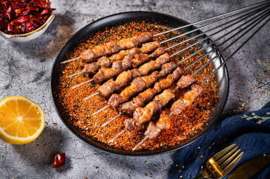 深色背景下放在盘子里的肥瘦烤羊肉串