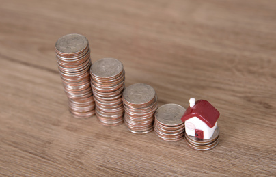 一排递减的美元硬币和一枚小房子模型