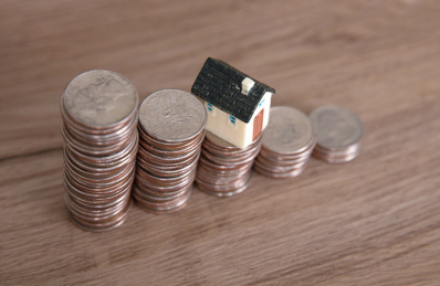 一排递减的美元硬币和一个硬币上的小房子模型