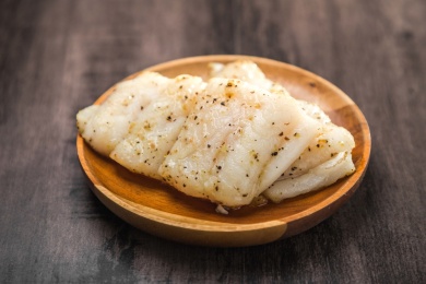 暗色木纹桌上放着一盘油煎龙利鱼排