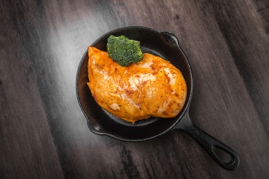 暗色木纹桌上放着盘煎新奥尔良鸡胸