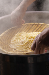 竹箕在大锅中捞起热腾腾的面