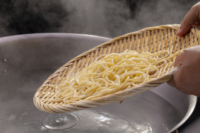 竹箕在大锅中捞起热腾腾的面