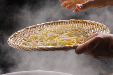 竹箕在大锅中捞起热腾腾的面