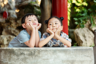 一位可爱的小男孩和一位美丽的小女孩趴在故宫的石桌上托着腮