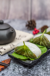 在紫砂壶和书法的中国风背景前有一盘中式小吃苏耗子