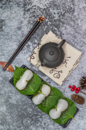 在紫砂壶和书法的中国风背景前有一盘中式小吃苏耗子