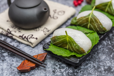 在紫砂壶和书法的中国风背景前有一盘中式小吃苏耗子