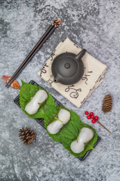 在紫砂壶和书法的中国风背景前有一盘中式小吃苏耗子