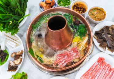 白色餐桌上的中国传统美食涮羊肉铜火锅和火锅食材
