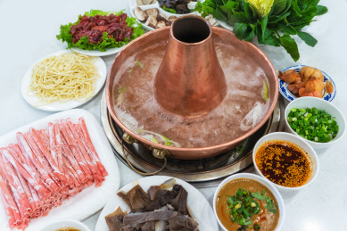 白色餐桌上的中国传统美食涮羊肉铜火锅和火锅食材