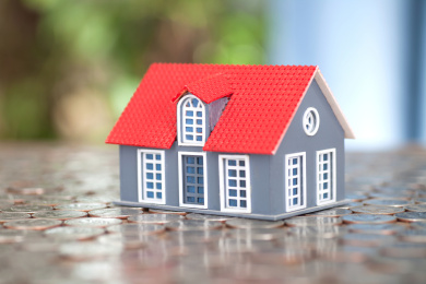 房屋模型放在铺满美元硬币的背景上