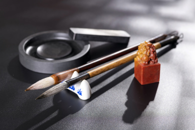 毛笔等文房四宝摆放在窗影下的黑色背景上