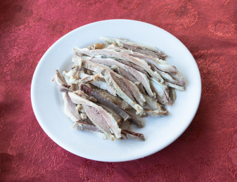 红色餐桌布上一盘白色瓷盘装的中国传统美食手抓羊肉