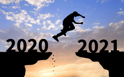 夕阳下背光剪影的山崖上一个剪影的人从2020年一端跳向2021一端