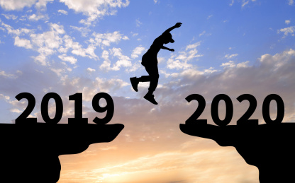 夕阳下背光剪影的山崖上一个剪影的人从2019年一端跳向2020一端