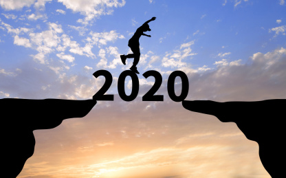 夕阳天空前两个剪影悬崖之间横着数字2020和数字上跳跃的人物剪影