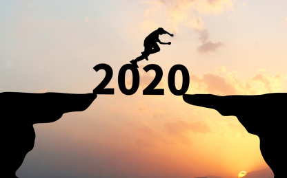 夕阳天空前两个剪影悬崖之间横着数字2020和数字上跳跃的人物剪影