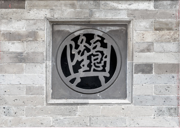 灰色砖墙上镶嵌的中国吉祥词砖雕合体字生意兴隆