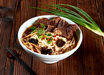 褐色木桌背景下的酱羊排汤面