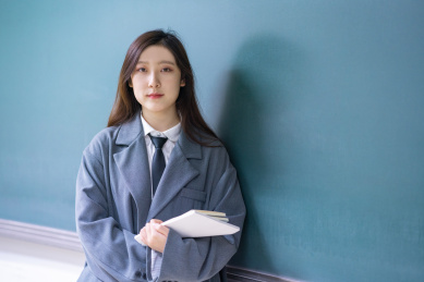 一个美女老师教室站在讲台前拿着书握拳加油鼓励鼓气教育概念