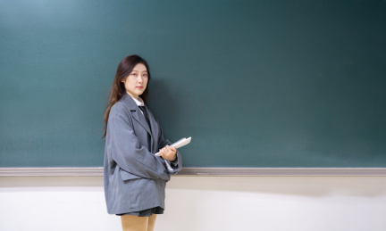 一个美女老师教室站在讲台前拿着书握拳加油鼓励鼓气教育概念