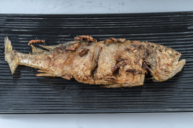 一条煎好的鱼放在长条形的黑色盘子上