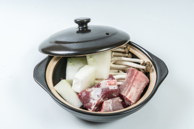 一个砂锅煲里装着未烹煮的冬瓜排骨和金针菇