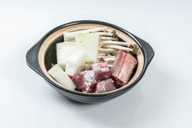 一个砂锅煲里装着未烹煮的冬瓜排骨和金针菇