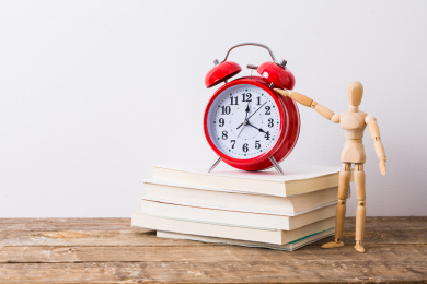 红色的闹钟和书籍，以及一个木偶在桌子上，学习概念
