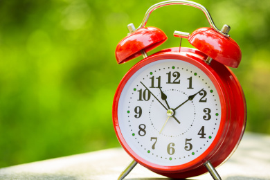 红色的闹钟在户外的桌子上,上午11点,自然背景