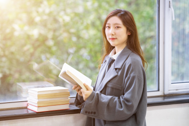 一个阳光美女大学生校花在图书馆窗户边看着书备考学习奋斗努力的学霸穿着校服读书阅读看书