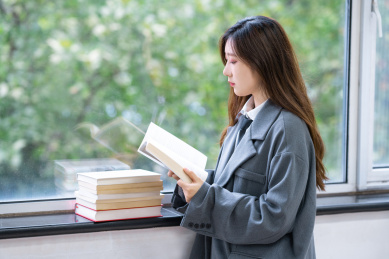 一个阳光美女大学生校花在图书馆窗户边看着书备考学习奋斗努力的学霸穿着校服读书阅读看书