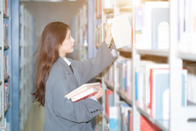 美丽的中国人美女正在图书馆认真的看着书籍书本阅读学习查询资料文献看书读书
