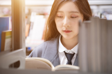 美丽的中国人美女正在图书馆认真的看着书籍书本阅读学习查询资料文献看书读书