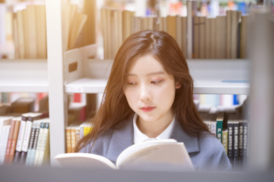 美丽的中国人美女正在图书馆认真的看着书籍书本阅读学习查询资料文献看书读书