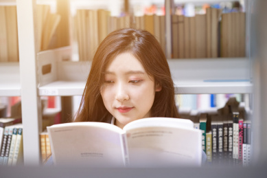 美丽的中国人美女正在图书馆认真的看着书籍书本阅读学习查询资料文献看书读书