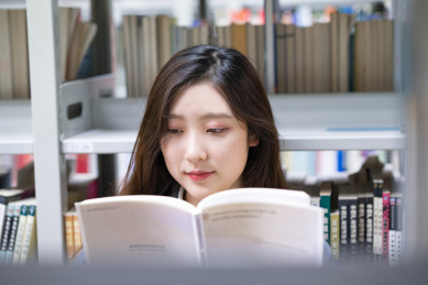 美丽的中国人美女正在图书馆认真的看着书籍书本阅读学习查询资料文献看书读书