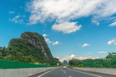 蓝天白云下从山脚经过的高速公路