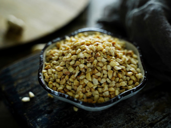 木背景上陶瓷小蝶中的花生碎