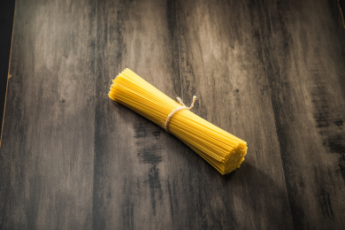 暗色木纹桌面上放着一捆意大利干面条