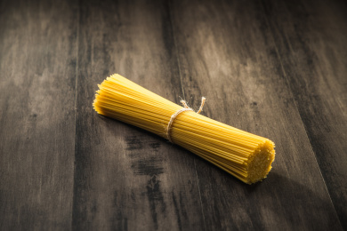 暗色木纹桌面上放着一捆意大利干面条