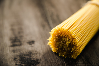 暗色木纹桌面上放着一捆意大利干面条