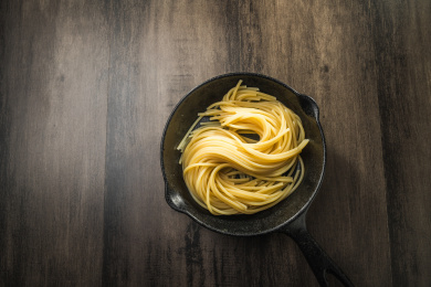 暗色木纹桌面上放着一盘煮熟的意大利面